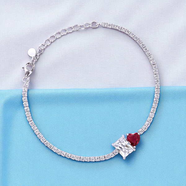 Silver bracelet with a red gemstone on a light blue background